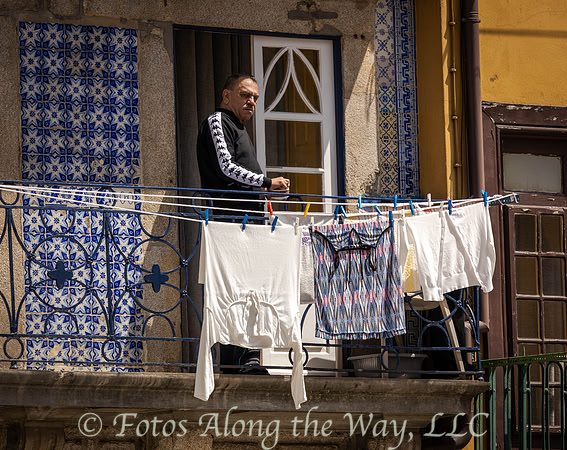 Man on Tiled Balcony Overlooking Busy Plaza (Portugal)